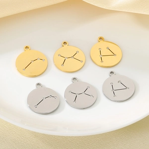 Detailed view of 18K gold and silver zodiac pendants with inset diamonds on silk