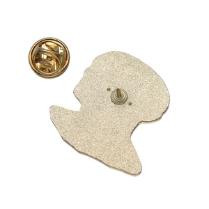Macro detail of the metal brooch back with gold butterfly clutch and textured finish