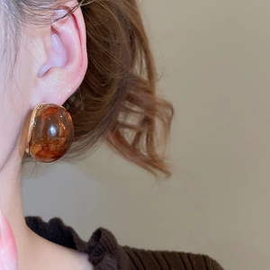 Close-up of vintage amber resin hemispherical stud earring worn by a model