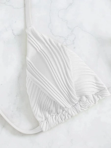 Dettaglio del top bikini bianco a costine con coppe a pieghe e laccetti da annodare