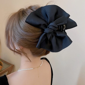 Dettaglio della grande clip per capelli con fiocco in tessuto nero opaco per acconciature