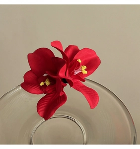 Detalle de una romántica pinza para el pelo con doble orquídea roja para vacaciones