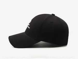 Detail of black cotton twill baseball cap with side embroidery and distressed brim