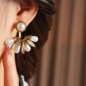 Close-up of fan-shaped vintage earrings with white pearls and sparkling marquise rhinestones