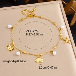 Detail view of gold ocean charms anklet with size specs on a beige jewelry tray