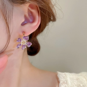 Close-up of a purple beaded flower earring worn by a model in a feminine style