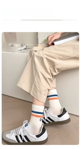Detail of crew socks with blue orange stripes and smiley embroidery on model wearing sneakers