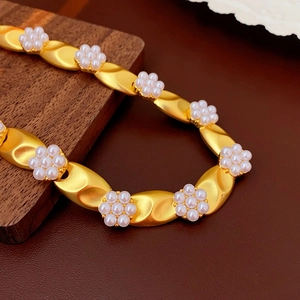Detailed macro of golden twisted chain with white pearl flowers in vintage court style