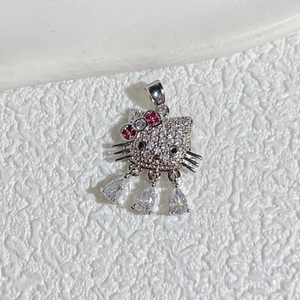 Macro shot of silver Hello Kitty pendant with white and red zircons on white background