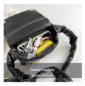 Internal capacity of black quilted puffer bag showing phone and cosmetics layout