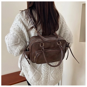 Brown vintage faux leather backpack on a model wearing a cozy cream knit sweater