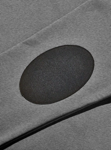 Close-up of gray knit fabric featuring a black oval elbow patch with precise stitching