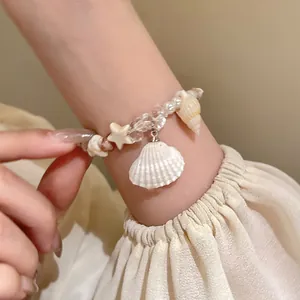 Detail shot of a beaded ocean charm bracelet featuring natural shells and starfish