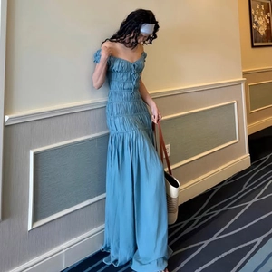 Détail d'une robe bleue à col en V avec texture plissée et jupe longue fluide sur mannequin