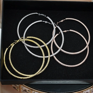 Macro detail of three oversized hoop earrings in gold silver and rose gold with rhinestones
