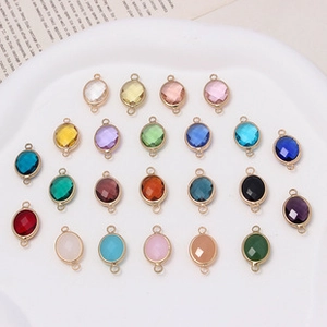 Flat lay of colorful oval crystal pendants with gold metal frames and double hanging loops