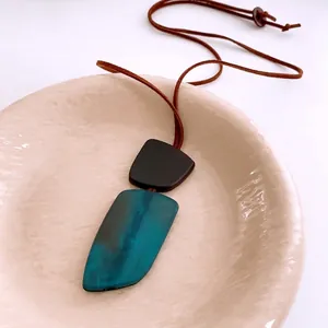 Irregular resin pendant necklace with marble texture on a white textured ceramic plate