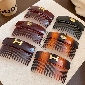 Detail view of retro acetate hair combs with gold metal accents on beige fabric background