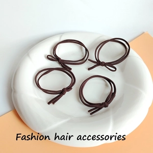 Detail of four brown high-elasticity hair ties with bows on a decorative ceramic plate