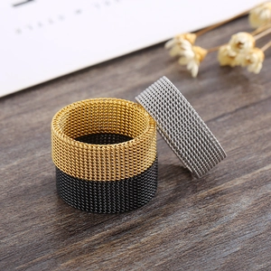 Close-up of woven mesh rings in gold, silver and black stainless steel on wood