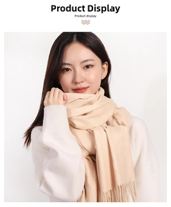 Detailed view of the soft knit texture and fringe edge on a cream cashmere-like scarf