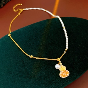 Gros plan détaillé du collier pendentif gourde plaqué or 18 carats avec perles sur velours