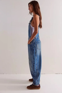 Side view of vintage washed blue denim overalls featuring cargo pockets and a loose fit