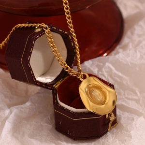 Macro shot of gold cowboy hat pendant necklace on vintage red velvet jewelry box