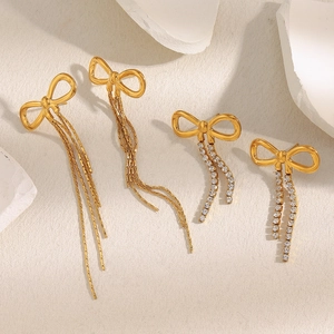 18K gold plated stainless steel bow earrings with zircon tassels on a stone display