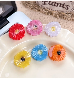 Detailed view of six colorful acetate daisy hair claws in a decorative tray
