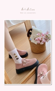 Close-up of pink suede Mary Jane shoes with cute cartoon bear patterned knit socks