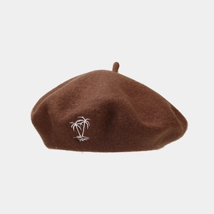 Detail of wool beret featuring a white palm tree embroidery on brown felt fabric