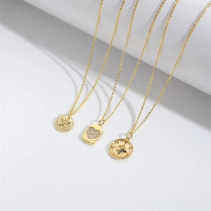 Three gold necklaces featuring star compass and heart pendants on white background