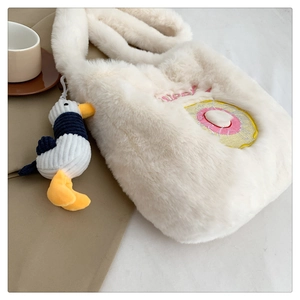 Detail of soft white plush shoulder bag with donut embroidery and corduroy duck charm