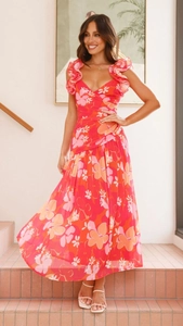 Détail d'une robe longue fleurie rose avec col en V et manches à volants sur un escalier