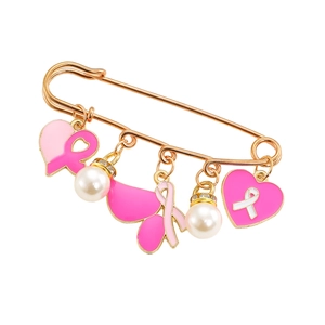 Détail des breloques ruban rose et perles sur une broche dorée contre le cancer du sein