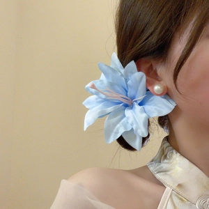 Close-up of light blue fabric lily hair clip worn on a side bun for a graceful look