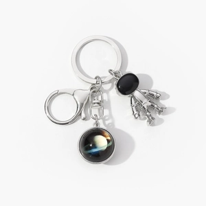 Detail of silver astronaut keychain with planetary pendant and secure lobster clasp