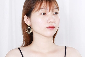 Detail of layered gold geometric circular drop earrings on a model for a minimalist look