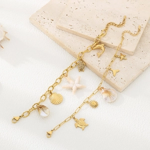 Détails d'un bracelet doré 18K avec breloques d'étoile de mer et coquillages marins