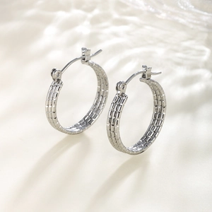 Detailed view of silver hoop earrings featuring intricate chain texture and polished finish