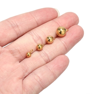 Polished gold stainless steel ball pendants in four sizes held for size comparison