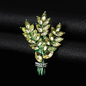 Macro shot of green enamel plant brooch featuring champagne marquise stones on black leather