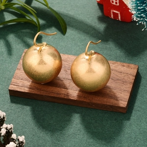 Gros plan de boucles d'oreilles boules dorées sur bois avec décor festif de Noël