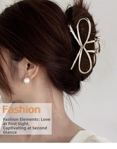 Detail of elegant gold metal bow hair claw clip styled on a woman's hair