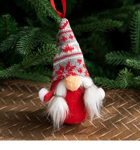 Detail of a handmade red Christmas gnome with a snowflake hat and white beard on pine