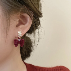 Gros plan des boucles d'oreilles nœud en velours bordeaux avec anneaux dorés et zircons