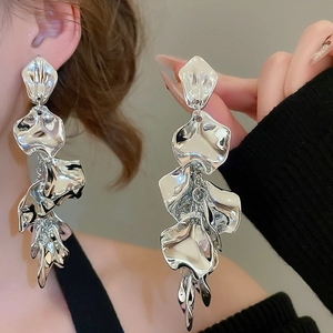 Macro shot of silver layered irregular flower petal earrings on a model with metallic shine