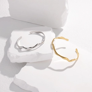 Macro shot of gold and silver wavy stainless steel bangles on white textured stone