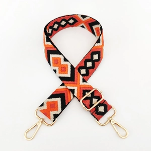 Close-up of geometric jacquard bag strap with orange and black ethnic patterns and gold hooks